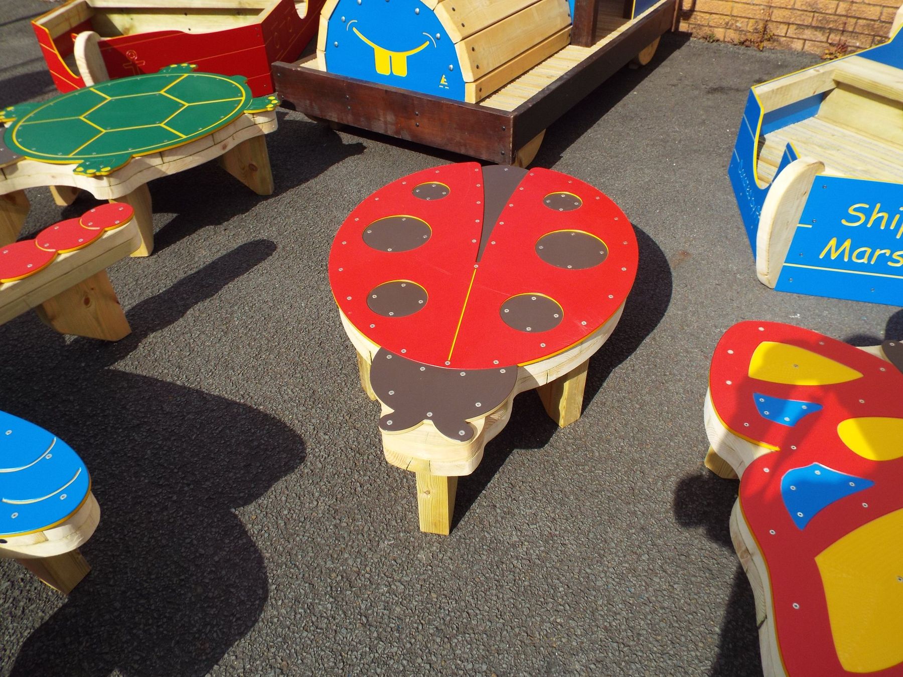 Child-sized timber picnic tables painted as a ladybird, a turtle and a butterfly
