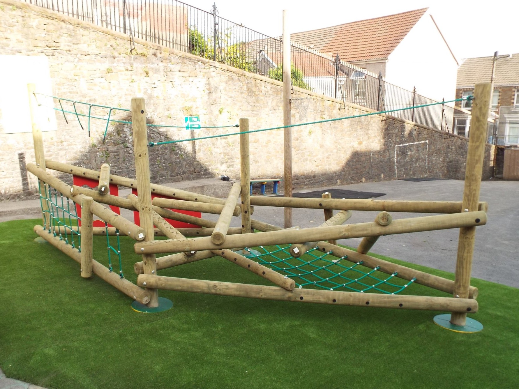 Timber trim trail with rope nets and balance beams on artificial grass