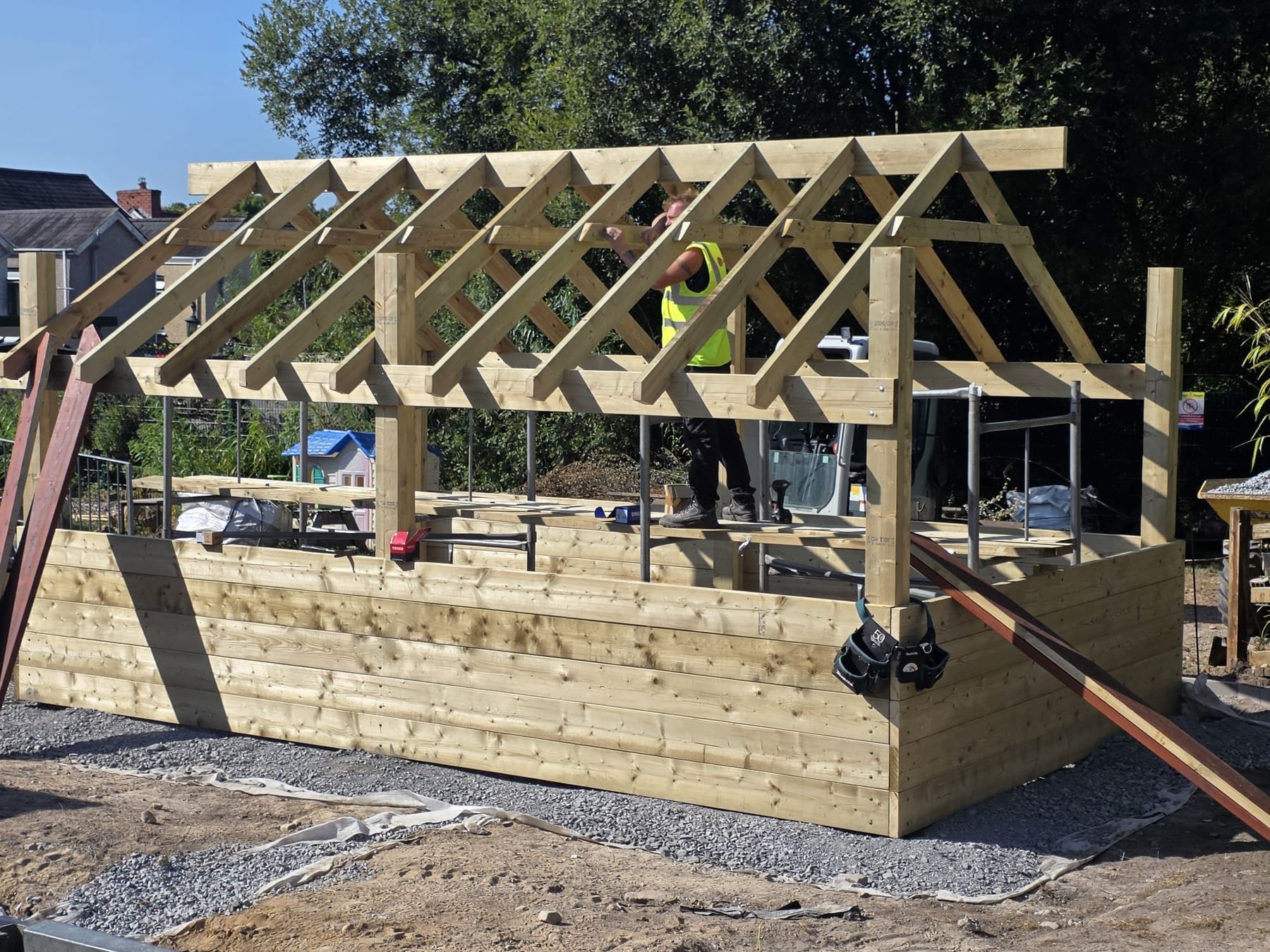 Roof trusses being fitted to the timber frame of a barn shelter during installation