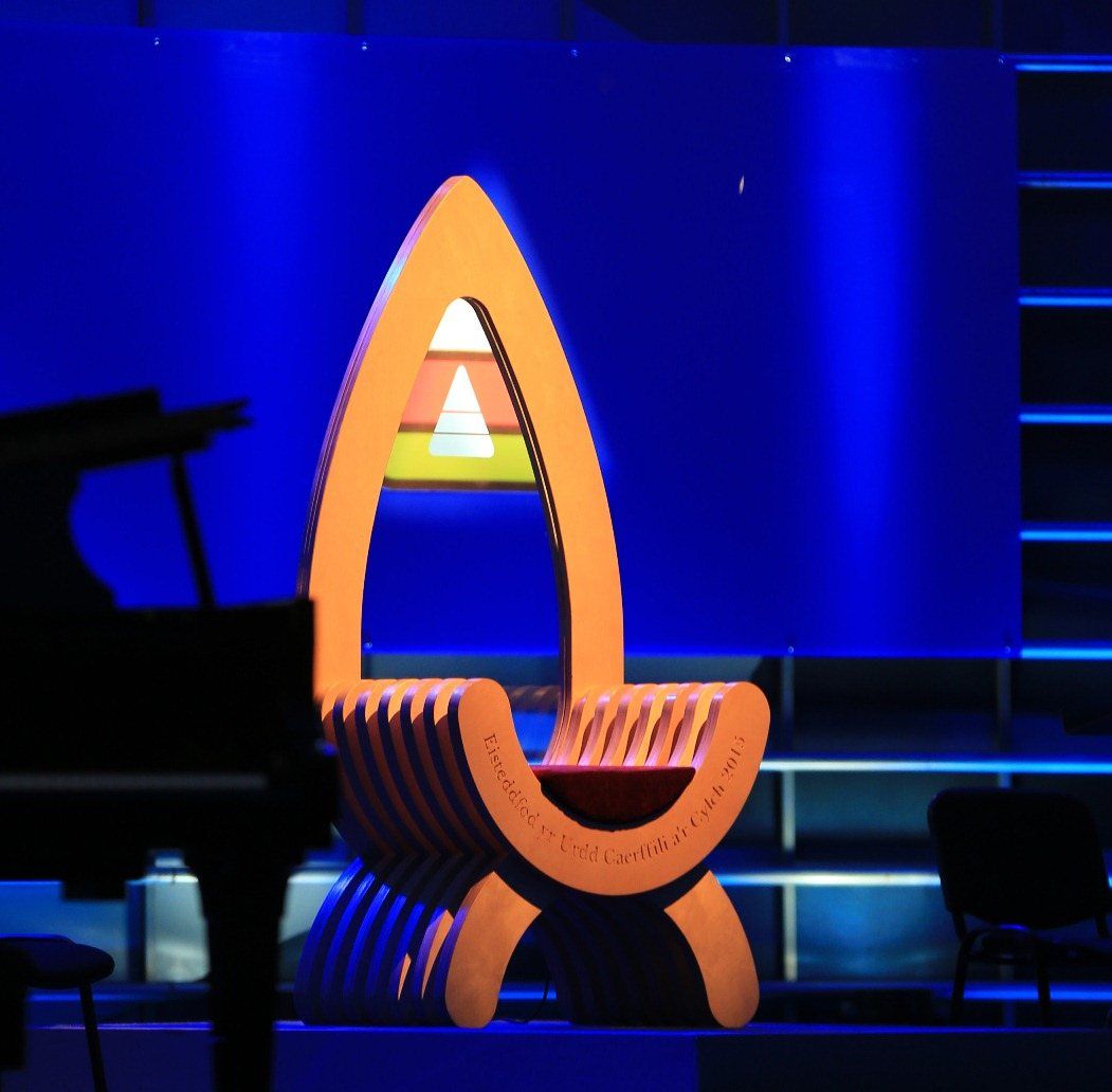 Carved timber Chair of the Bard on a stage under blue lighting