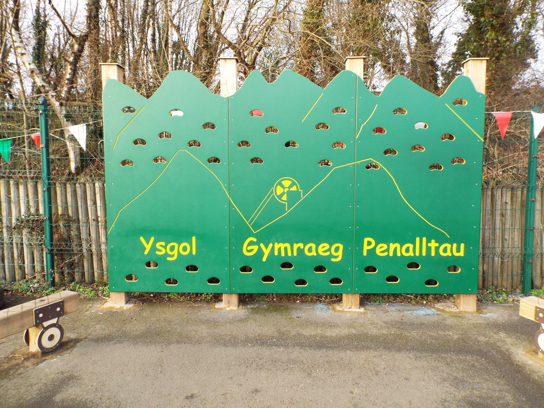 Green timber climbing panel carved Ysgol Gymraeg Penalltau, with a mountain outline