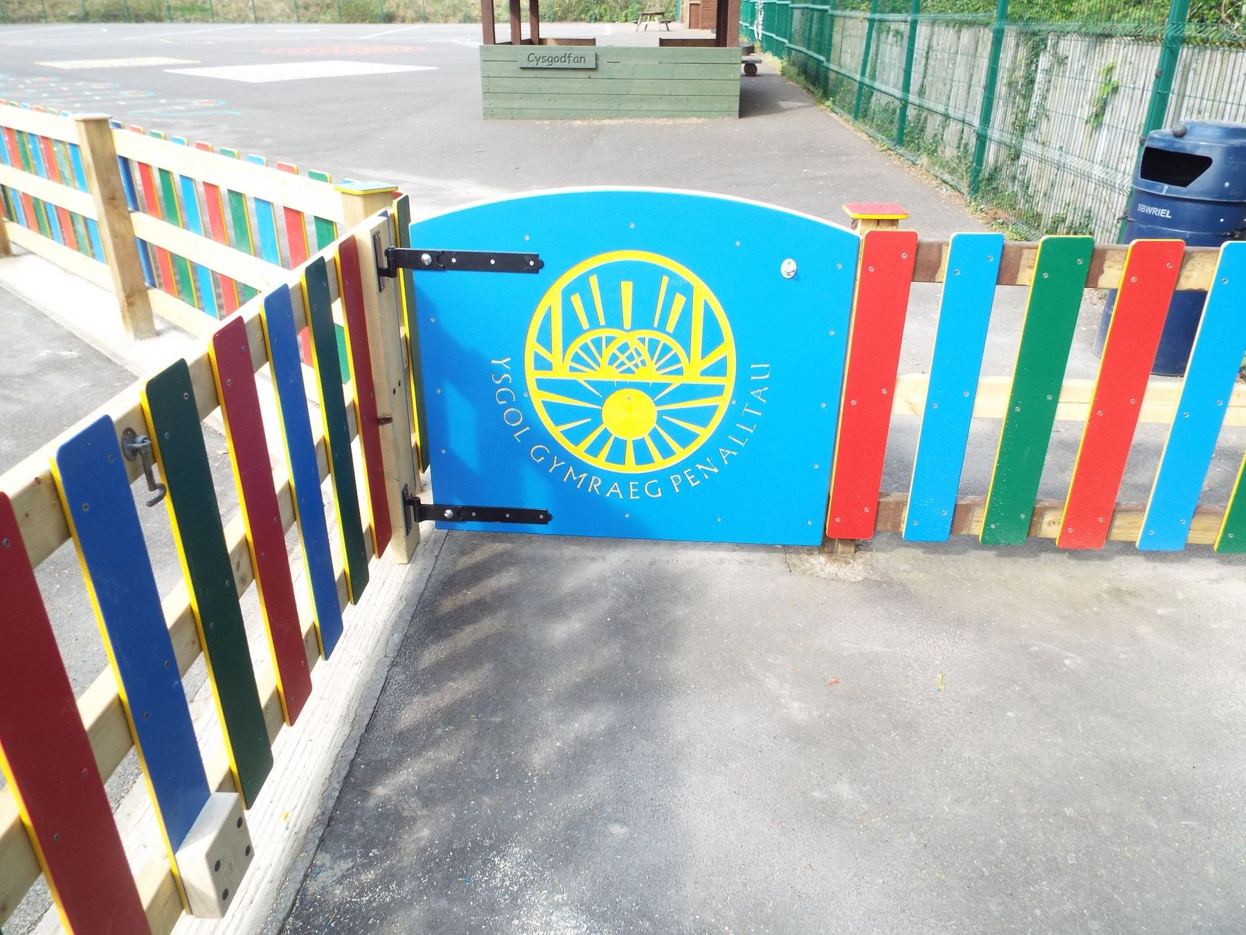 Timber fencing with brightly painted pales and a matching gate around a playground