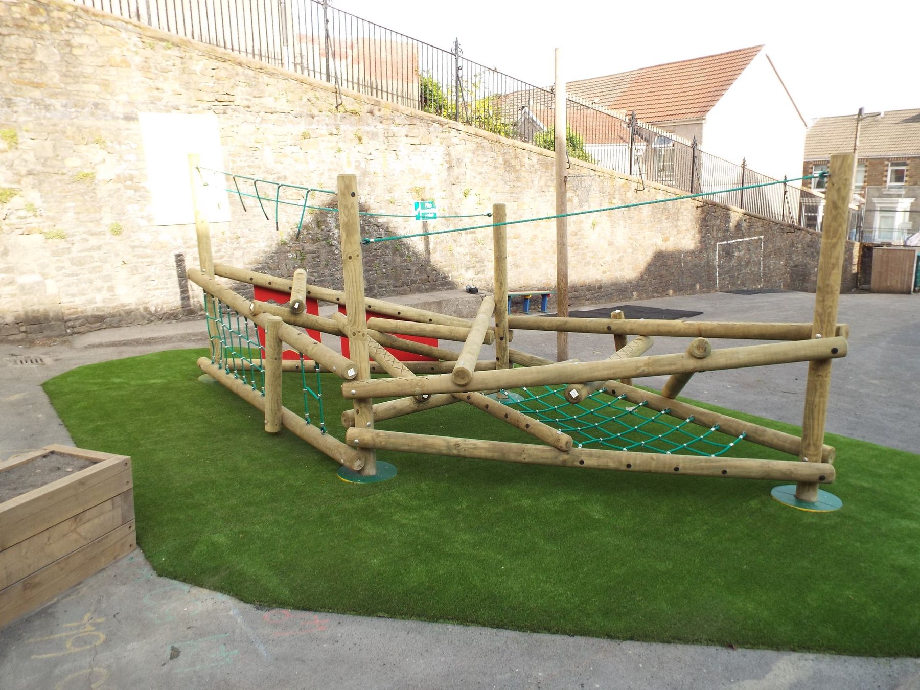 Timber climbing structure with nets and ropes on artificial grass