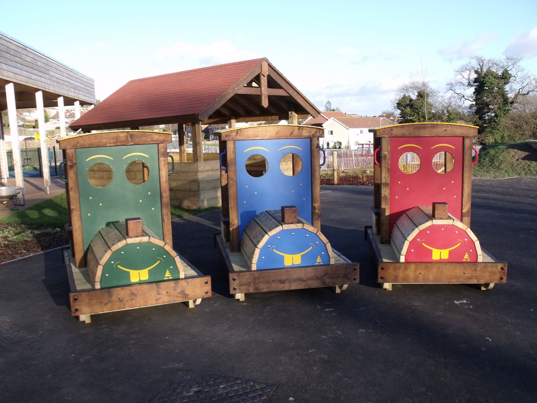 Timber play train with three brightly painted carriages in a playground